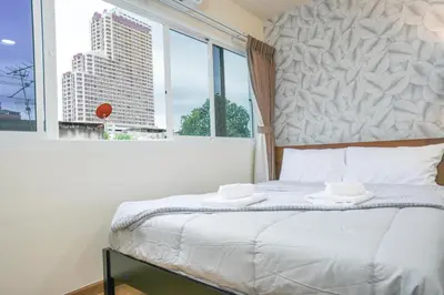 a bedroom with a bed with a large window at Deluxe Gam-Hom Hostel เจริญนคร in Bangkok