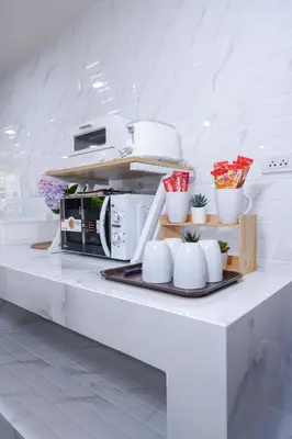 a kitchen with a white counter with a microwave at Deluxe Gam-Hom Hostel เจริญนคร in Bangkok