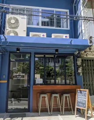 a restaurant with stools in front of a blue building at LCT Hostel Bangkok in Bangkok