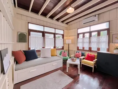 a living room with a couch and some windows at Rare Find 80 yrs Heritage Peaceful House in BKK in Bangkok Yai