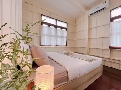 a bedroom with a bed with white walls and windows at Rare Find 80 yrs Heritage Peaceful House in BKK in Bangkok Yai
