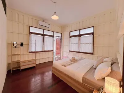 a bedroom with a large bed and two windows at Rare Find 80 yrs Heritage Peaceful House in BKK in Bangkok Yai
