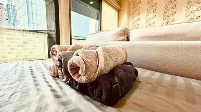 a room with a couch and a bed with towels at Noble Remix Thonglor - Direct BTS Access - Super Fast Wi-Fi in Bangkok