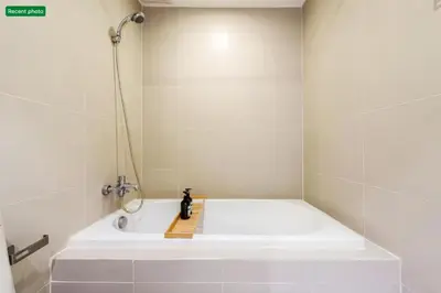a white bath tub in a bathroom with a shower at Noble Remix Thonglor - Direct BTS Access - Super Fast Wi-Fi in Bangkok