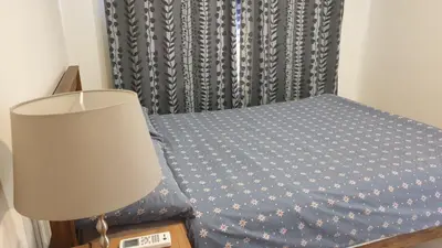 a bedroom with a bed with a lamp and a curtain at Manor Riverfront Stay, Chaophraya View Condo, Nonthaburi in Ban Tha It (1)