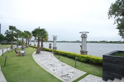 a park next to a body of water with palm trees at Manor Riverfront Stay, Chaophraya View Condo, Nonthaburi in Ban Tha It (1)