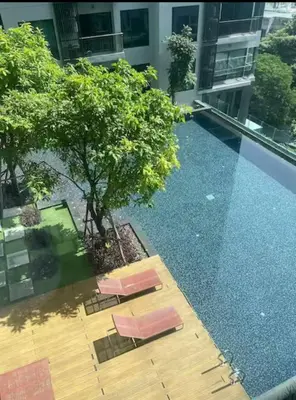 an empty swimming pool with two chairs and a tree at Peaceful Stylish and cozy condo in Khlong Toei