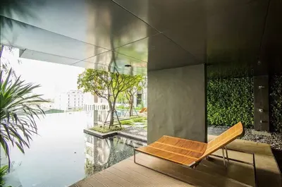 a wooden chair sitting on a deck next to a pool at Peaceful Stylish and cozy condo in Khlong Toei