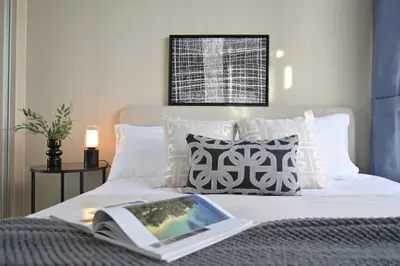 a book laying on top of a bed with pillows at 5min Metro | KingBed | Kitchen full | Netflix WiFi in Khlong Toei
