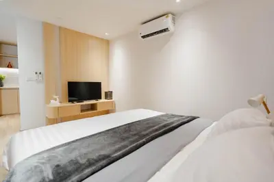a white bedroom with a bed and a tv at I-Zen Residence Central Eastville in Bangkok