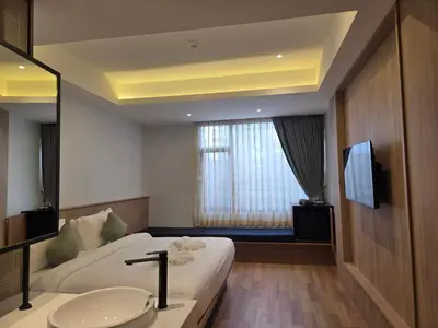 a bedroom with a bed and a sink and a television at Warm Pillow Hotel Bangkok in Bangkok