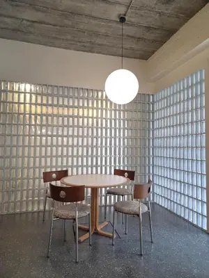 a table and chairs in a room with a wall of windows at Warm Pillow Hotel Bangkok in Bangkok