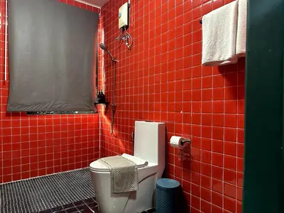 a red tiled bathroom with a toilet and a shower at Delightful Townhouse in the Heart of Sukhumvit in Bangkok