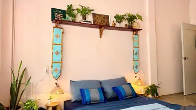a bedroom with a bed and plants on a wall at Baan YentaFo - Pink House in Talad Noi in Chinatown