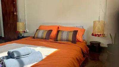 a bedroom with a bed with orange sheets and pillows at Baan PadSeeEw - Rooftop Riverview in Khlong San