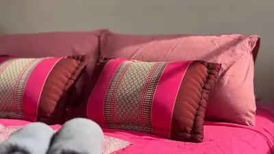 a person sitting on a bed with two pillows at Baan PadSeeEw - Rooftop Riverview in Khlong San