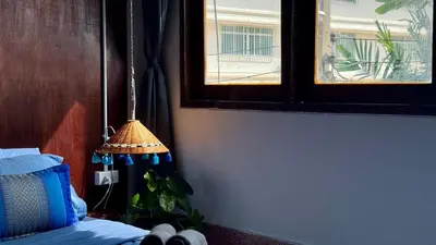 a bedroom with a bed and a window and a lamp at Baan PadSeeEw - Rooftop Riverview in Khlong San