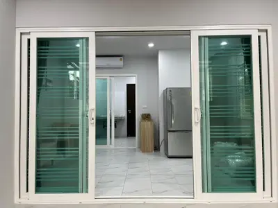 a sliding glass door in a kitchen with a refrigerator at Cozy Corner in Samut Prakan