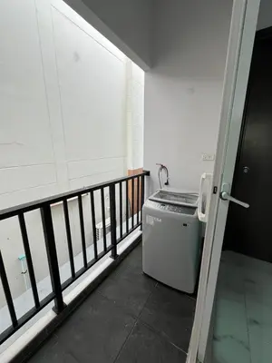 a small refrigerator in a room with a balcony at Cozy Corner in Samut Prakan