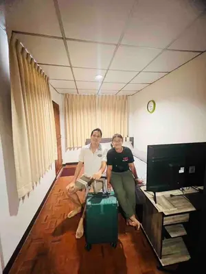 two people sitting in a room with a suitcase at Palmhouse studio room in Bang Khen
