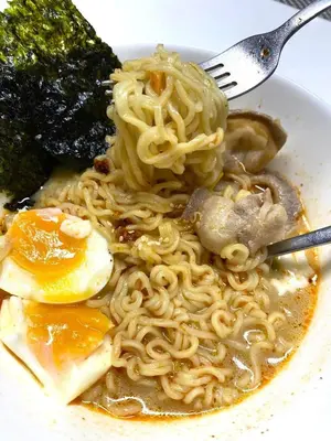 a plate of noodles with a fork and broccoli at AkkHouse in Ban Bang Toei (1)