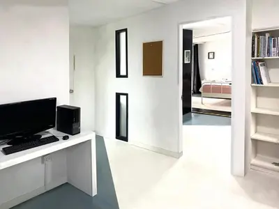 a room with a desk with a computer and a bedroom at AkkHouse in Ban Bang Toei (1)