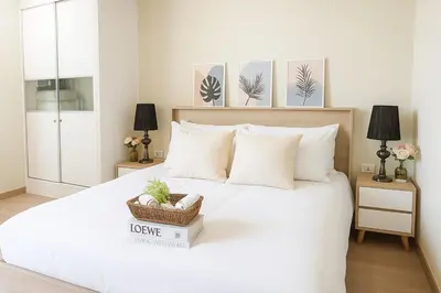a bedroom with a large white bed with a basket on it at Executive 1 BR and Sofa bed Next to T21 Asoke BTS in Bangkok