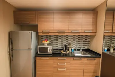 a kitchen with wooden cabinets and a stainless steel refrigerator at Modern 2 Bed Executive Unit 5min to Nana BTS in Bangkok