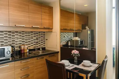 a kitchen with wooden cabinets and a table with chairs at Modern 2 Bed Executive Unit 5min to Nana BTS in Bangkok