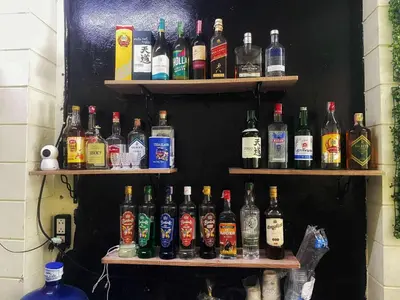 a wall with shelves filled with bottles of alcohol at Happy Hope Khao San in Bangkok
