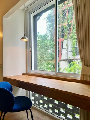 a window with a blue chair in front of it at day one space - BTS On Nut - Live Above Cowork Cafe in Bangkok
