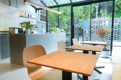 two tables and chairs in a restaurant with windows at day one space - BTS On Nut - Live Above Cowork Cafe in Bangkok