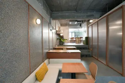 a row of tables and benches in a room at day one space - BTS On Nut - Live Above Cowork Cafe in Bangkok