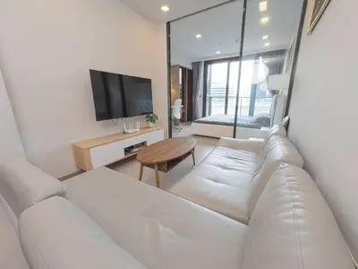 a living room with a white couch and a tv at KINGbed with Pool Gym and Standing Desk near MRT in Bangkok