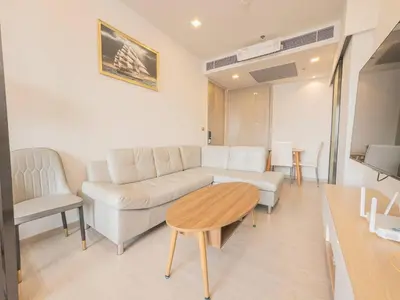 a living room with a white couch and a table at KINGbed with Pool Gym and Standing Desk near MRT in Bangkok