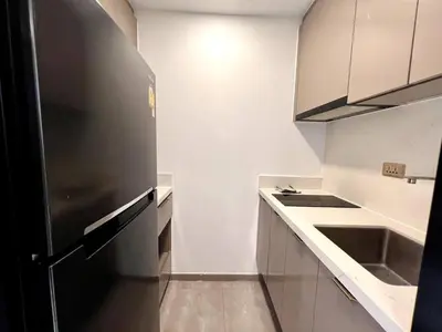 a kitchen with a black refrigerator and a sink at King Bed with Living Room Pool and Gym MRT 200m in Ban Na Song