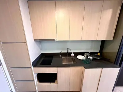 a small kitchen with wooden cabinets and a sink at High Floor Loft with Pool and Gym in Ban Na Song