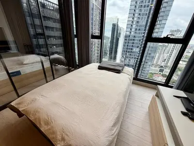 a bedroom with a bed in front of a large window at Spacious Apt with King Bed Pool and Gym MRT200m in Bangkok