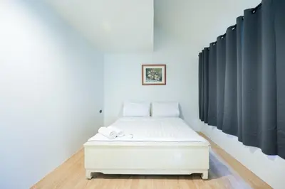 a white bed in a room with black curtains at XX สแนปอิน สุขุมวิท 1 - Snap Inn Sukhumvit 1 in Makkasan