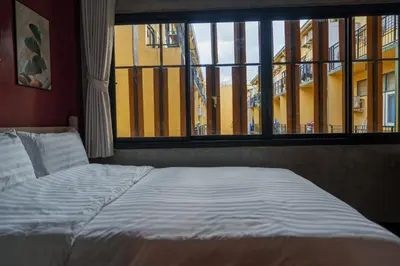 a bed in a room with a large window at Wat We See Bangkok Hostel in Bangkok