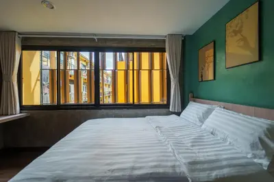 a bedroom with a large bed with a window at Wat We See Bangkok Hostel in Bangkok