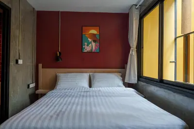 a bed in a bedroom with a red wall at Wat We See Bangkok Hostel in Bangkok