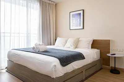 a bedroom with a large bed with a blue blanket at Dazzle Residence ByPinny in Bangkok