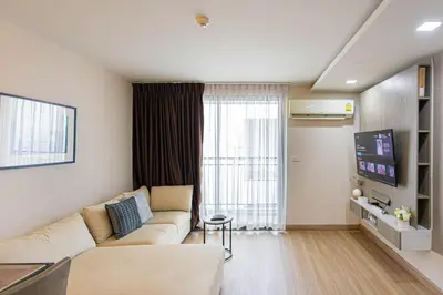 a living room with a couch and a large window at Dazzle Residence ByPinny in Bangkok