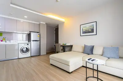 a living room with a couch and a kitchen at Dazzle Residence ByPinny in Bangkok