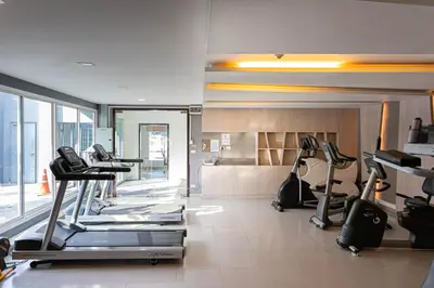 a gym with treadmills and ellipticals in a room at Dazzle Residence ByPinny in Bangkok