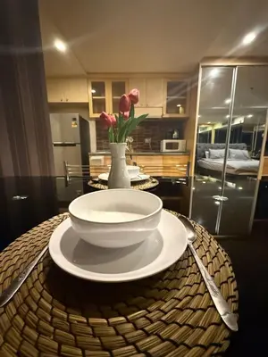 a table with a bowl and a vase with flowers at Modern Suite near BTS Nana Netflix Sky View in Makkasan