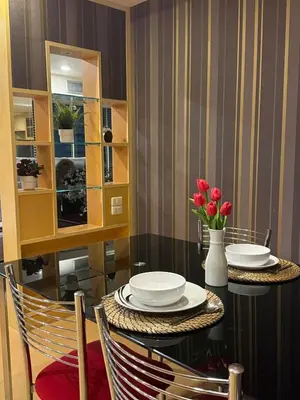 a dining room with a table with plates and flowers at Modern Suite near BTS Nana Netflix Sky View in Makkasan