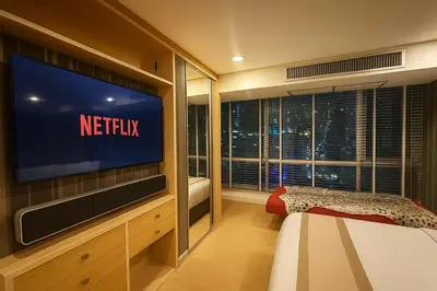 a bedroom with a television and a window with a netflix sign at Modern Suite near BTS Nana Netflix Sky View in Makkasan