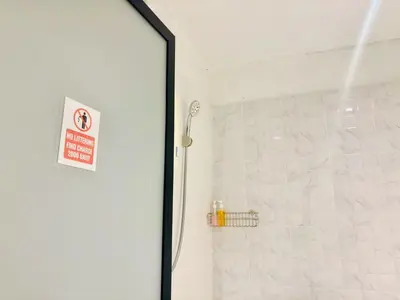 a bathroom with a shower with a sign on the door at Sukhum Charoen Krung Tak-Sin bridge guest house in Bangkok